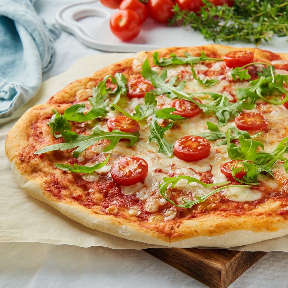 Kings Duck Bar&Grill's fresh pizza with cherry tomatoes, mozzarella, and arugula on a wooden board.